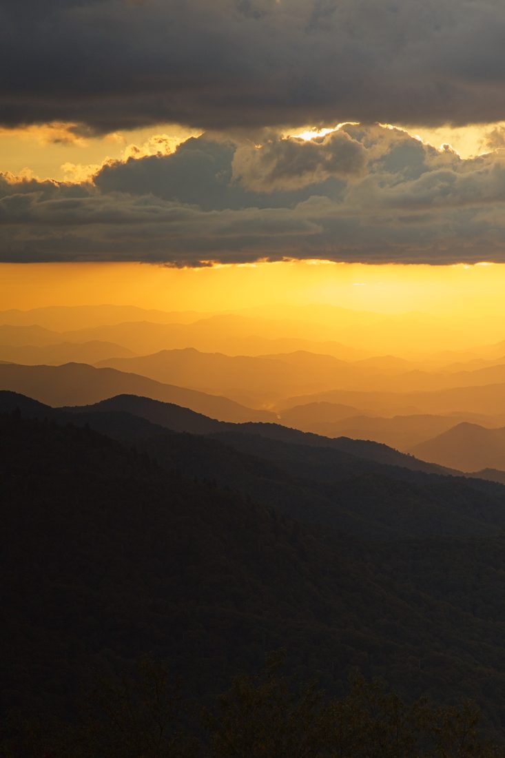Vertical view of layered mountain ridges glowing in golden sunset light
