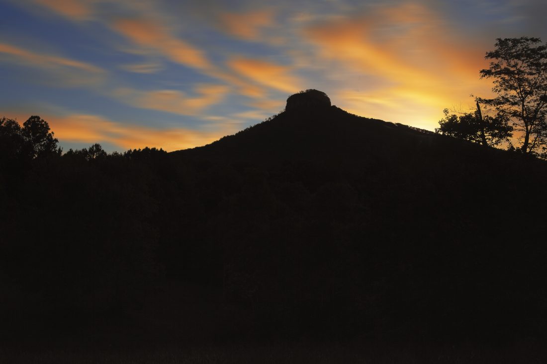 Pilot Mountain silhouette under colorful sunset clouds